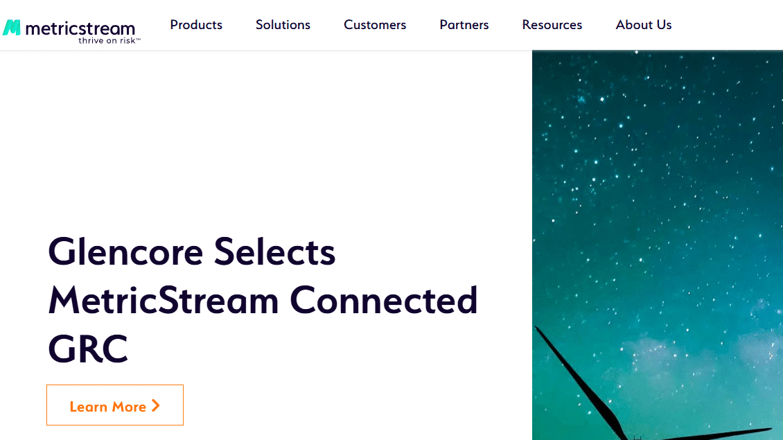 Screenshot of the MetricStream homepage featuring an announcement about Glencore selecting MetricStream Connected GRC. The design includes a background image of wind turbines under a starry sky.